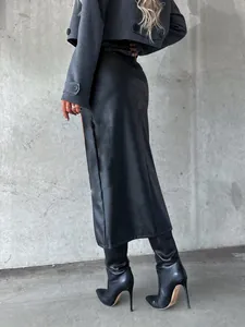 Detail view of a long black high-slit skirt paired with stylish leather boots