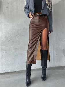 Detail of a chic high-slit brown faux leather midi skirt for women styled with black boots