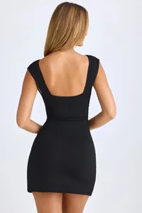 Macro view of the backless detail on this black sleeveless bodycon slimming dress