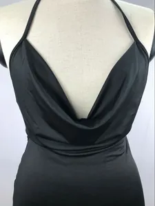Detail view of the black halter cowl neck dress featuring smooth and glossy fabric texture.