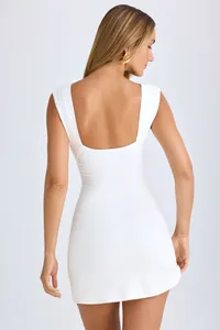 Detailed back view of white sleeveless ruched bodycon mini dress with low scoop back
