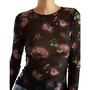 Dettaglio di maglia nera in rete trasparente a maniche lunghe con motivi floreali paisley.