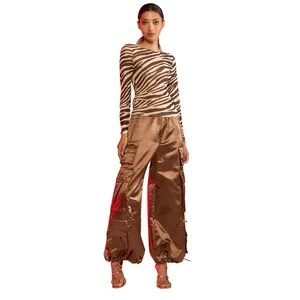 Vista completa di modella con top in mesh zebrato e pantaloni cargo in raso marrone.