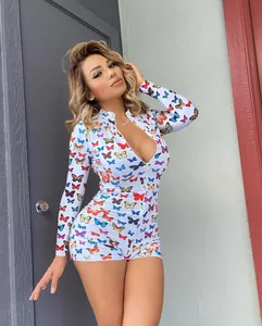 Dettaglio di una tutina a maniche lunghe bianca con stampa farfalle colorate e scollo a V zip.