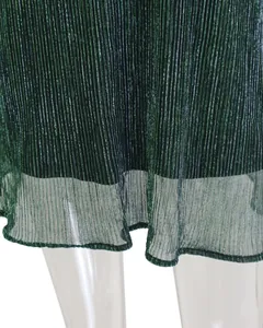 Nahaufnahme des plissierten Metallic-Stoffs und des transparenten Saums des grünen Kleides
