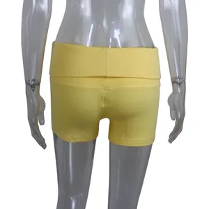 Macro detail view of slim-fit yellow ribbed cotton yoga shorts with a folded waistband