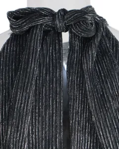 Detailaufnahme der plissierten Metallic-Neckholder-Schleife an einem schwarzen Minikleid