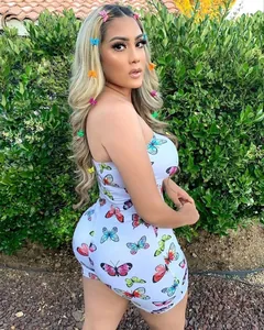 Detailansicht eines weißen Overalls mit Schmetterlingsdruck an einem Modell im Garten