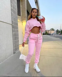 Woman wearing a pink two-piece cropped hoodie and jogger set outdoors on a sidewalk