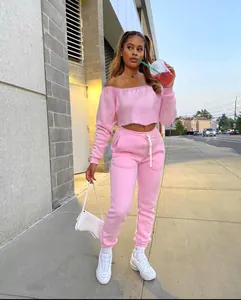 Street lifestyle view of a model wearing a pink off-shoulder two-piece tracksuit set