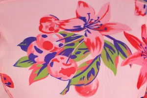 Gros plan sur l'imprimé numérique de fleurs et cerises sur tissu en maille rose.