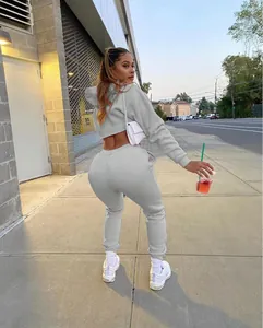 Women's grey two-piece cropped hoodie and sweatpants set shown in an outdoor street setting