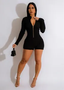 Detailed view of a sexy black textured knit romper featuring a V-neck with gold zipper detail