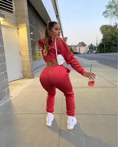 Side view of woman wearing red fleece two-piece sportswear set in an urban street setting