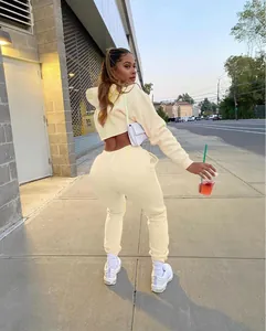 Outdoor back view of a women's cream solid color cropped hoodie and sweatpants tracksuit set