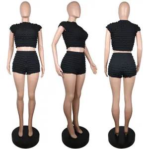 Vista de tres ángulos de un conjunto negro de punto burbuja con top corto y shorts a juego