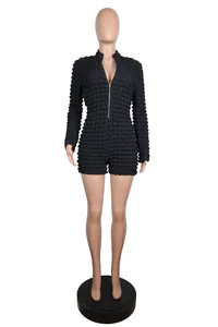 Front view of black bubble textured knit romper showing V-neck design and front zipper detail