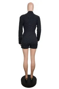 Back view of black popcorn textured long sleeve romper showing unique fabric detail.