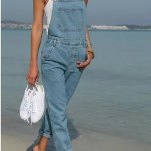 Casual women's light blue denim overalls jumpsuit with front pocket for beach outings