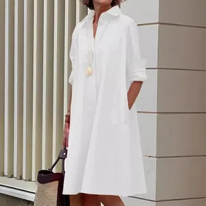 Minimalist white loose long sleeve shirt dress for women in an elegant outdoor setting