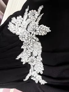 Vista macro del intrincado aplique floral de diamantes de imitación en vestido de noche negro.