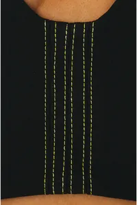 Detailed view of neon green vertical stitching on black fabric of a French style bandeau dress