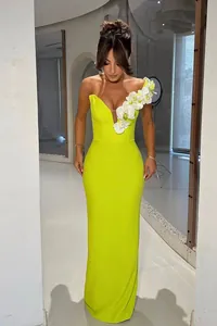 Detailed front view of a lime yellow one-shoulder bandage dress with orchid decorations.