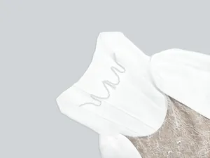 Close-up detail of elegant white bandage dress with floral lace and pearl accents