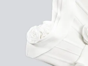Detailed macro view of elegant white 3D fabric flower accents on a textured bandage dress