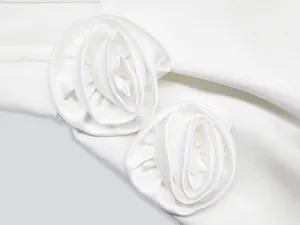 Detailed view of handmade white 3D satin flower ornaments on a bandage party dress