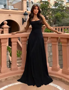 Elegant floor-length black formal dress with a pleated skirt in a classic architectural setting.