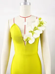 Close-up view of a lime green bandage dress featuring elegant white orchid shoulder flowers