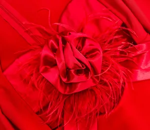 Close-up of a decorative red satin rose with feathers on an evening bandage dress.