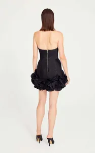 Back view of black strapless cocktail dress with voluminous ruffled hem and gold zipper