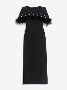 Detalle de elegante vestido de noche negro con plumas de avestruz y capa de diamantes