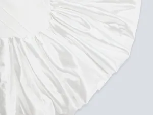 Macro primo piano che mostra la trama e le pieghe del tessuto in raso bianco di un abito da festa
