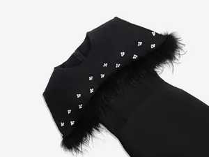 Primer plano de vestido bandage negro con ribete de plumas de avestruz y detalle strass