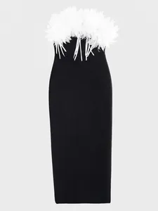 Detalle del vestido bandage negro con adorno de flores blancas en el escote.