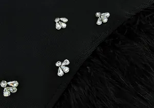 Detalle de cerca de mariposas de strass brillantes en un vestido negro con plumas de avestruz.