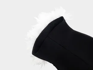 Detalle de flores de plumas blancas en un vestido de noche tipo vendaje negro