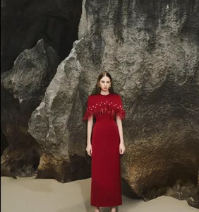 Detalle de vestido de noche rojo de Navidad con capa decorada con plumas de avestruz