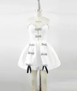 Detailweergave van witte bandagejurk met strass strikversieringen en zwarte linten.
