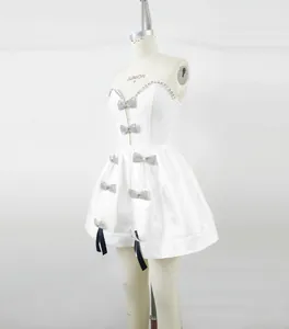 Zijaanzicht van witte bandage mini-jurk met strass strikken en zwarte lintdetails