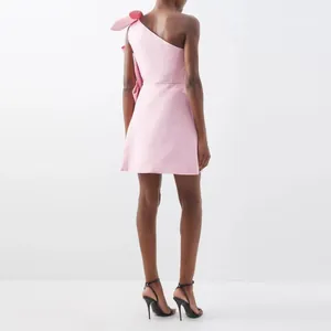 Detailed back view of a pink satin one-shoulder mini dress featuring a large bow detail
