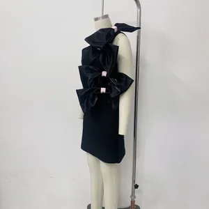 Black satin mini dress with large bow accents and pink ribbons shown on mannequin