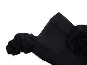Close-up detail of black ruffled cocktail dress showing premium stitching and texture.