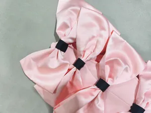 Close-up of elegant pink satin bows with black ribbons on a sweet girlish party dress.