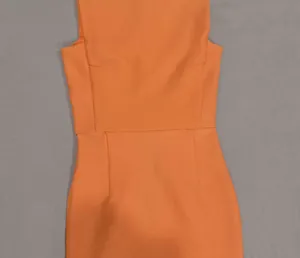 Primo piano dell'abito in maglia arancione che mostra cuciture e trama del tessuto.