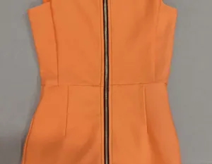Dettaglio dell'abito in maglia arancione con cerniera centrale anteriore e trama a costine.