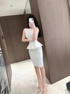 Detail view of white peplum knit top and bandage bodycon skirt set worn by a model